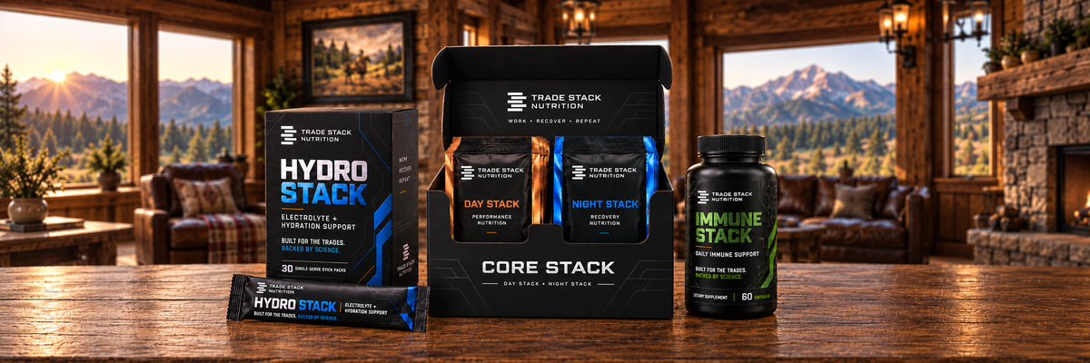 A group of sports nutrition products from Core Stack, including a Hydro Stack packet, a core stack box with three daily/nightly packets, and an Immune Stack bottle, arranged on a wooden table in a rustic cabin living room with a mountain view.
